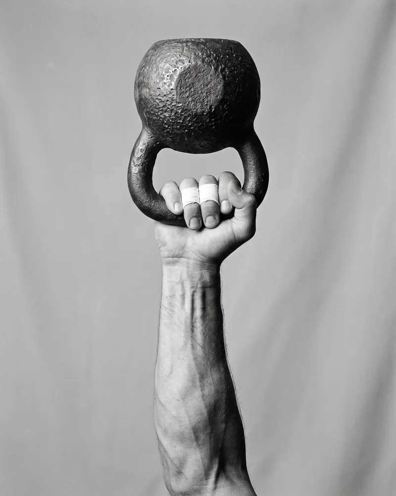 A forearm holding a cast-iron kettlebell overhead